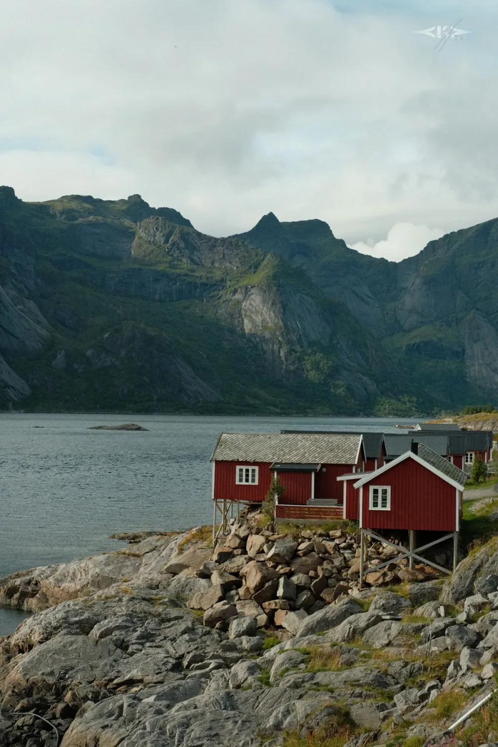 Red fishing cabins on the rocks below Lofoten peaks